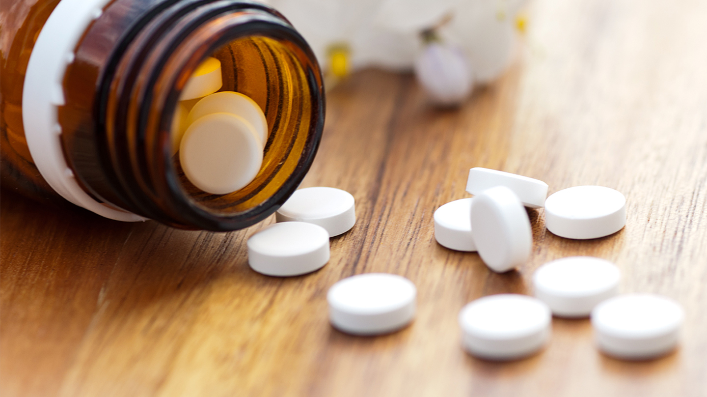 Schüßler-Salze: Braunes Gläschen mit Schüßler-Salz-Tabletten liegt auf einem Holztisch, davor einzelne weiße Tabletten. Schüßler-Salze: Braunes Gläschen mit Schüßler-Salz-Tabletten liegt auf einem Holztisch, davor einzelne weiße Tabletten.